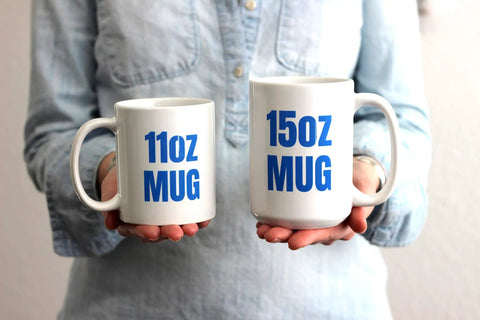 Person holding 11oz and 15oz white ceramic mugs with bold blue text for comparison.