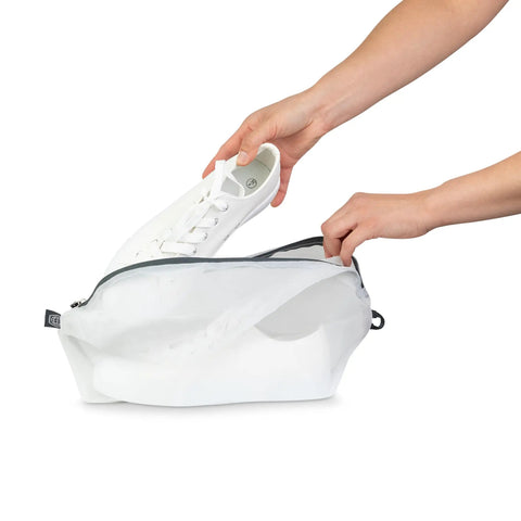 Person placing white shoe into Large Compression Packing Cube Set With See Through Mesh for Travel Organizers, Space Saving Luggage Cubes.