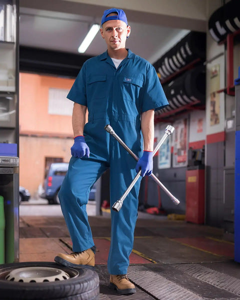 Mens Short Sleeve Coveralls Shop Grade Mechanic Jumpsuit With Deep Utility Pockets Rugged Cotton Poly Blend in blue, in garage setting.