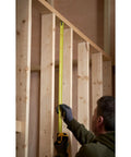 Person using Tape Measure With Blade Armor Built Tough 8 M Metric, Shock Resistant, Mylar Coating, wide 32mm blade indoors.