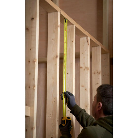 Person using Tape Measure With Blade Armor Built Tough 8 M Metric, Shock Resistant, Mylar Coating, wide 32mm blade indoors.