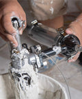 Close-up of hands using Drywall Box Filler Valve For Joint Compound Pumps, Heavy Duty Billet Aluminum Body With Hard Coat Anodized Finish.