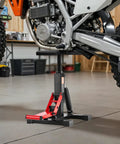 Side view of Dirt Bike Lift Stand With 1200Lb Capacity, Hydraulic Motorcycle Jack holding a dirt bike for maintenance in a garage.