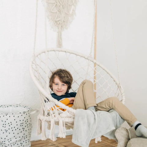 Child sitting in Bohemian Macrame Hammock Chair Swing With Hardware Kits For Indoor And Outdoor Use Ideal For Balcony Porch Yard Or Bedroom Cozy Supportive Knitted Seat With 265 Pound Capacity And Easy Hanging, indoors.