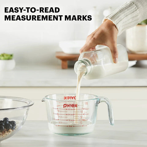 Person pouring milk into 4 Cup Glass Measuring Cup For Baking And Cooking With Easy To Read Ounces And Milliliters, Dishwasher Safe