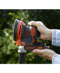 Badass 18V Cordless Orbital Sander With Killer Dust Control And Super Smooth Softgrip Handle For Hassle Free Wood Projects 12,000 Opms Compact Orange Design shown in hand with battery pack.