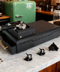 Top Shelf Electric Knock Box With Rapid Spin Motor For Hassle Free Puck Cleanup Non Slip Base, espresso setup on marble counter.
