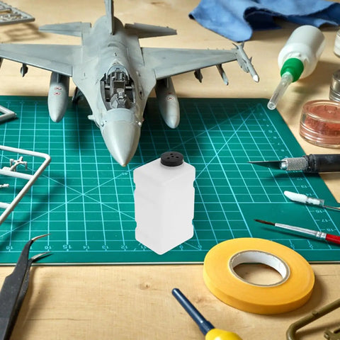 Clear 120CC RC Plane Fuel Tank Set With Metal Tubing And Engine Container on a hobby table with model aircraft