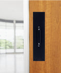 Commercial 15 Inch Stainless Steel Pull Door Plate In Matte Black Finish mounted on a wooden door in an industrial setting.