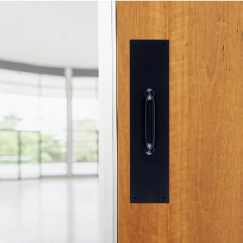 Commercial 15 Inch Stainless Steel Pull Door Plate In Matte Black Finish mounted on a wooden door in an industrial setting.
