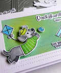 Handmade card featuring stitched rectangle frame die cuts, decorated with a dachshund illustration, kite, and playful sentiment on green background.