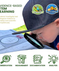 Child inspecting owl pellet with magnifying glass, part of Owl Pellet Dissection Kit For Classrooms, Big 1 Pack, Hands On Biology STEM Activity.