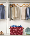 Collapsible Canvas Storage Basket With Waterproof Interior And Sturdy Handles For Bedroom Closet Organization, holding rolled denim in a red butterfly design.