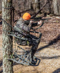 Hunter using Titan Sd Climbing Treestand With Roomier Design Bigger Top Seat Frame And Longer Foot Platform For Large Frame Hunters