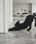 Black Eco Friendly Door Stopper With Soft Impact Absorbing Block shaped like a cat holding a door open on a tile floor