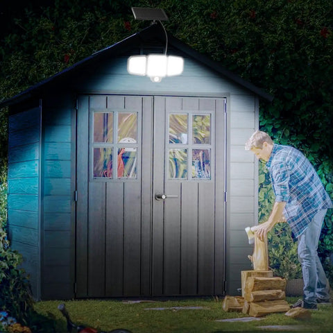 Game Changer Outdoor Solar Flood Lights illuminating a garden shed at night, 3-head design with remote control visible