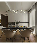 Modern Wave LED Pendant Light Featuring Brushed Gold Finish And Clean Geometric Lines above a dining table in a contemporary setting.