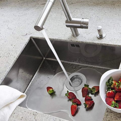 Stainless Steel Sink Strainer Basket 2.25 Inch Drain Cover in use, catching debris in a kitchen sink while strawberries wash over it.