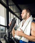 Man in gym holding Smooth Operator 40oz Stainless Steel Vacuum Insulated Water Bottle With Straw And Spout Lids Kept Ice Cold For Two Full Days Fits Every Car Cup Holder For Weekend Drifts Summer Vibes And Travel Black.