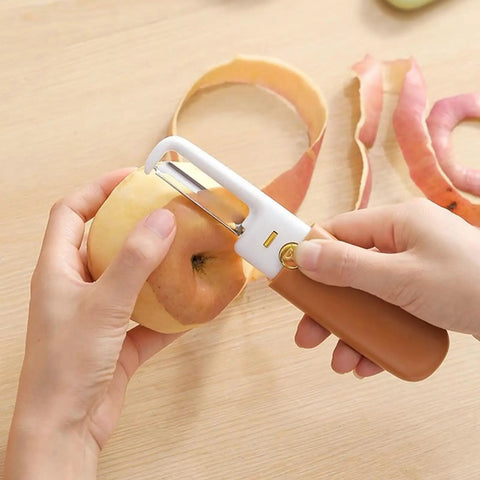 Person using Stainless Steel Fruit Peeler Knife For Kitchen And Camping Use, Portable Double Head With Orange Handle to peel apple