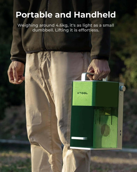 Green XTOOL handheld laser engraver with white carrying handle, side vents visible