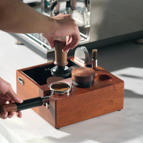 Person using Eight In One Espresso Knock Box And Barista Grade Coffee Accessories Organizer with Natural Walnut Base on counter.