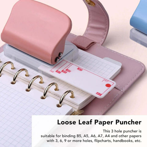 Pink handheld 3-hole paper punch for binders and notebooks punches up to five pages at once with clean 5.5mm holes, shown with notebook