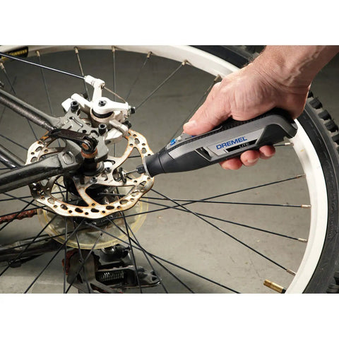 User operating Ultra Compact Four Volt Cordless Rotary Tool Featuring Variable Speed And No Sweat Accessory Swaps for bike repair.
