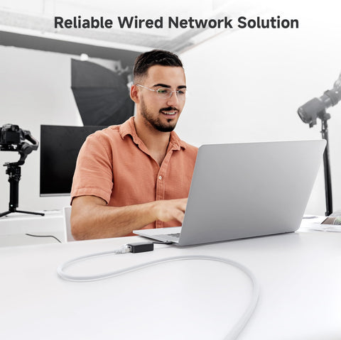Man using laptop with 10Gbps Snagless Shielded Cat6a Ethernet Cable 10ft White Built For Lightning Fast Home Office Networks Premium Shielded RJ45 Cord