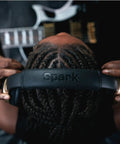 Person wearing Spark NEO Wireless Guitar Headphone Amp And AI Powered Guitar Rig, holding headphones with guitar in background.