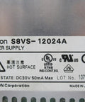 Close-up of Omron S8VS-12024A DIN rail power supply label with safety and certification markings, indicating solid state design.