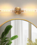 2-Light Gold Wall Sconces, Modern Bathroom Vanity Light with Glass Shades above a round mirror with greenery.