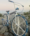 White BMX bike with blue accents on rocky terrain at sunset, showing adjustable 400mm bicycle seat post with tilt head and easy install clamp.