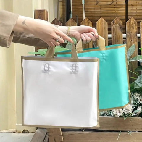 Hands holding two high-end paper gift bags in teal and white, showcasing durable handles and elegant design for weddings or parties.