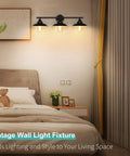 Industrial Rustic 3 Light Vanity Wall Sconce in Dark Bronze with Vintage Gold Trim illuminating a cozy bedroom with bed, artwork, and decor