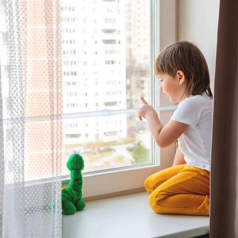 Child sitting by window secured with 4 Pack Adjustable Sliding Door Security Bars With White Rubber Tips Tension Rods 9.8 To 15.7 Inch