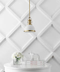 Brass Gold Modern Industrial 10 Inch Pendant Light With White Dome Shade installed in a modern interior above a white table.