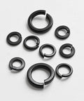 Assorted sizes of Three Eighths Inch Split Lock Washer Set, 50 Pack, Black Oxide 304 Stainless Steel Spring Lock Washers on white surface.