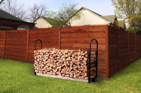 Outdoor Heavy Duty Firewood Log Rack Kit With Adjustable Bracket storing wood against a wooden fence, black powder coated steel, 42 inch tall