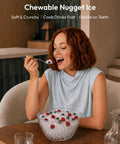 Woman enjoying fresh nugget ice from a bowl, highlighting the soft sonic pebble ice from the Fresh Freeze Countertop Nugget Ice Maker Yields 42 Lbs Soft Sonic Pebble Ice In Minutes With Smart App Alexa Hookup Self Cleaning Portable Pick For Home Office And Backyard Hangouts.