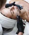 Black vinyl disposable exam gloves on an esthetician during facial treatment