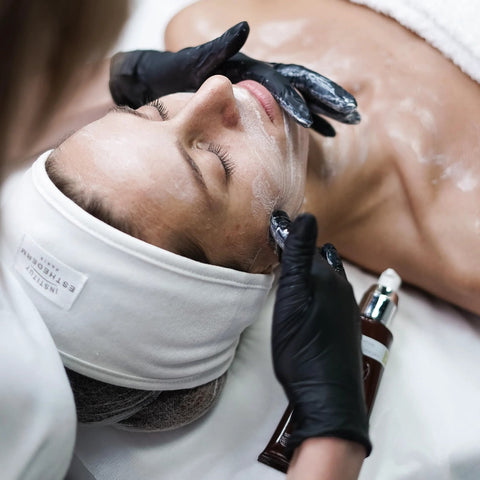 Black vinyl disposable exam gloves on an esthetician during facial treatment