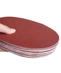 Close-up of "30 Pack 8 Inch Self Adhesive Sanding Discs Set Grit 80 100 120 180 240 400 For Drywall Floors Woodworking And Metal Projects Sticky Back Sandpaper Discs Great For Paint Prep Rust Busting Deburring And Smoothing" stack held by a hand.