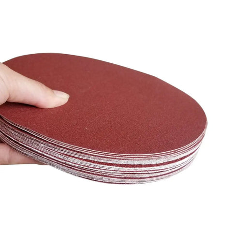 Close-up of "30 Pack 8 Inch Self Adhesive Sanding Discs Set Grit 80 100 120 180 240 400 For Drywall Floors Woodworking And Metal Projects Sticky Back Sandpaper Discs Great For Paint Prep Rust Busting Deburring And Smoothing" stack held by a hand.