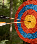 Backyard Archery Target Three Layer Thick Straw Circular Target with color rope surface hit by arrows outdoors.