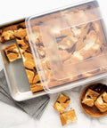 Natural Aluminum High Sided Sheet Cake Pan For Even Browning And Big Batches with brownies and storage lid on marble surface.