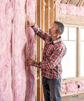 Premium Pink Fiberglass Insulation Batts For Interior Walls And Attic Cavities Heavy Duty Unfaced Design being installed on wall.