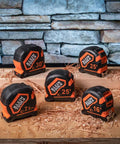 Multiple heavy duty tape measures with various lengths on a wooden surface.