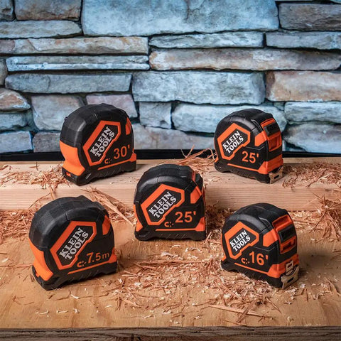 Multiple heavy duty tape measures with various lengths on a wooden surface.