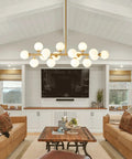 Mid Century Modern Sputnik Chandelier With 16 Lights Brushed Brass Arms And Frosted Milk Glass Shades hanging over a cozy seating area.
